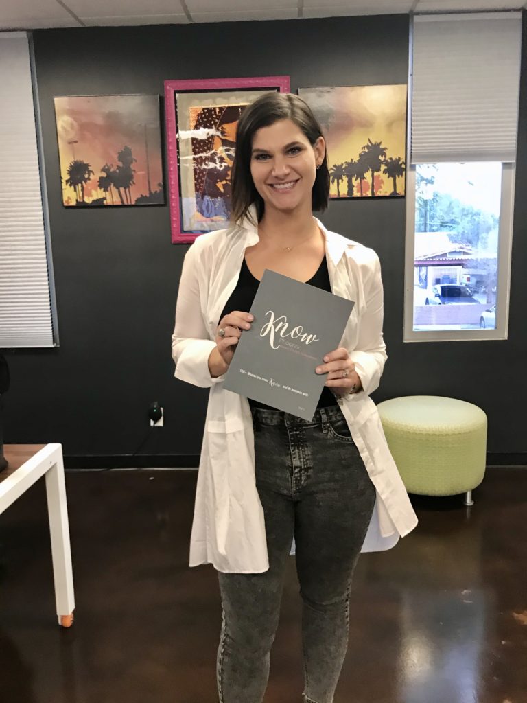 Sarah Benken, founder and CEO of KNOW Books + Tribe holding her KNOW book for The Women's Eye podcast
