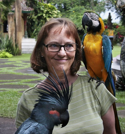 Laurie McAndish King, curious traveler author of "An Elephant Ate my Arm" with parrots/ courtesy Laurie King